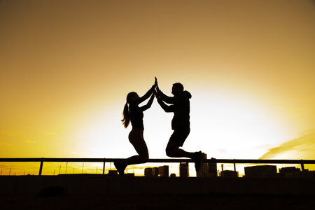 Athletes jumping and high-fiving at sunset in the cityの写真素材