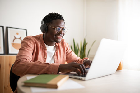 Young man working from home enjoying online meeting using laptop and headphonesの写真素材