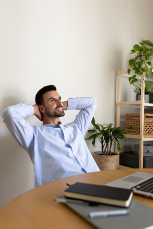 Vertical portrait of happy caucasian male entrepreneur relaxing at home office taking a break feeling satisfaction.の写真素材