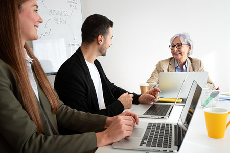 Happy people working at the office, talking and using laptops.の写真素材