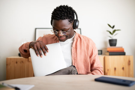 Young man putting laptop in backpack after working from homeの写真素材