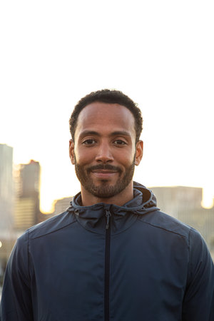 Confident male athlete smiling after training outdoors in urban settingの写真素材