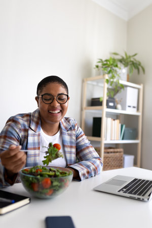 Smiling businesswoman enjoying healthy lunch at her deskの写真素材