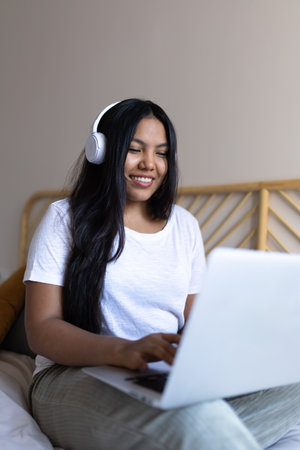 Young woman working from home using laptop and headphones smilingの写真素材