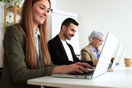 Three people working at the office using laptops.の写真素材