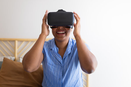 Excited woman using virtual reality headset at homeの写真素材