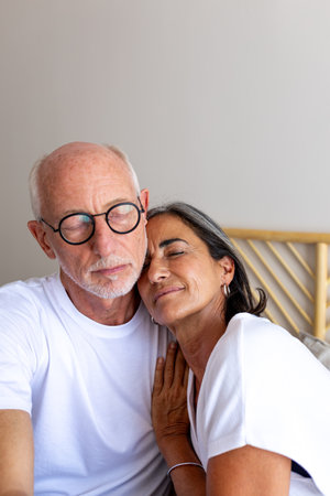 Vertical portrait of mature couple relaxing together at home. Eyes closed. Feeling connection and love. Copy space.の写真素材