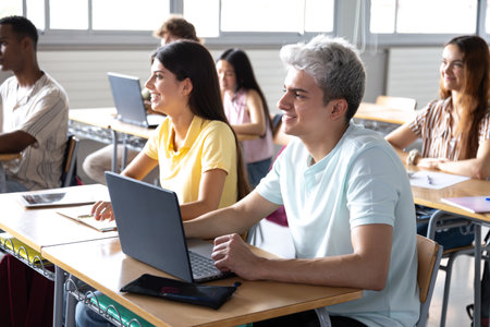 University students using laptops following a lecture in classroomの写真素材