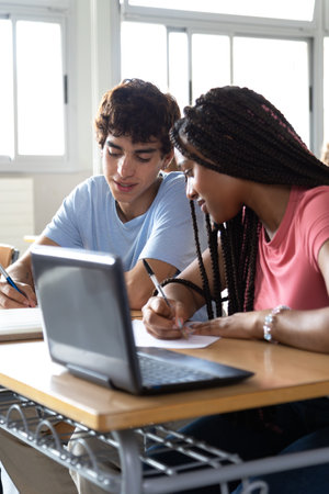 High school students working together on a project using laptop in classroomの写真素材