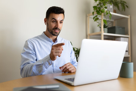 Male entrepreneur using laptop. Business man on online meeting video call at home office using wireless earphones.の写真素材
