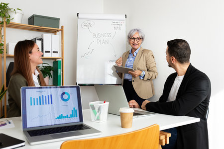 Senior business woman giving presentation to sales and marketing team at the office.の写真素材