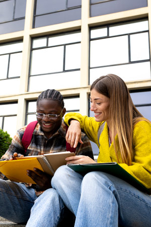 Smiling students studying together outdoors on university campus