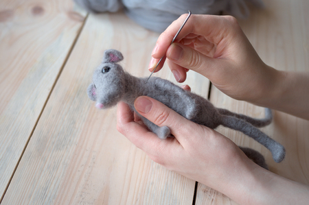 felting wool toy close-up hands on wooden backgroundの写真素材