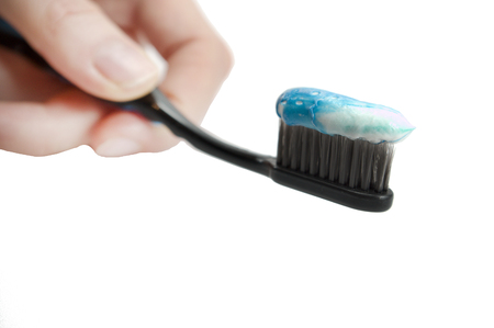 black toothbrush with the minty color of toothpaste in the girl's hand on a white background, isolatedの写真素材