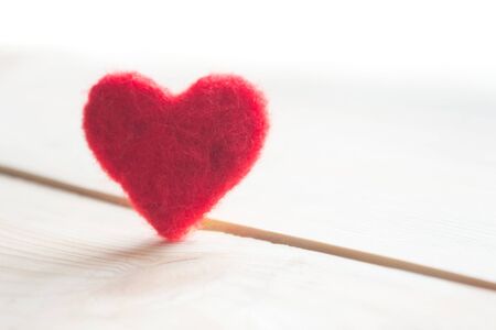red heart handmade of wool on wooden background, a symbol of love, bright sun backgroundの写真素材