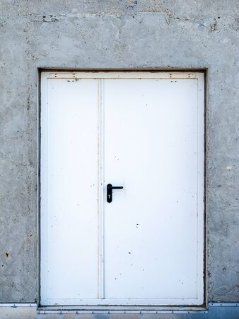 iron white metal door in concrete wall, front viewの写真素材