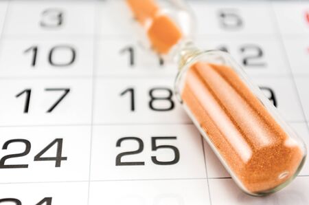 hourglass on the background of the calendar for the month, end of the month, deadline, reports, completion and delivery of worksの写真素材
