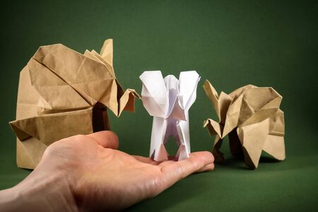 origami elephant and baby elephant made of craft paper on green background, paper and forest conservation concept, save paper save the forest, mockup, copy spaceの写真素材