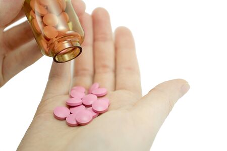 multicolored tablets of different size in hand top view close-up macro, isolated, white backgroundの写真素材