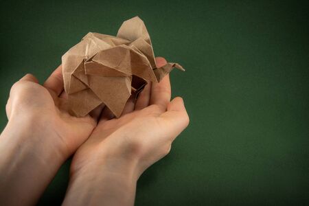 origami baby elephant craft paper on a green background on the hand, the concept of saving paper and forests, save paper, save the forest, protect wildlife, mockup, copy spaceの写真素材