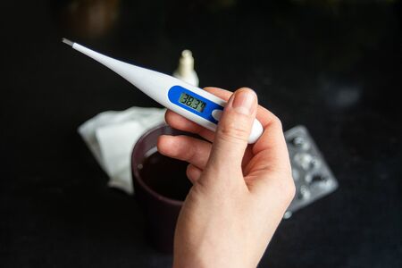 electronic thermometer in hand shows high temperature, fever, disease