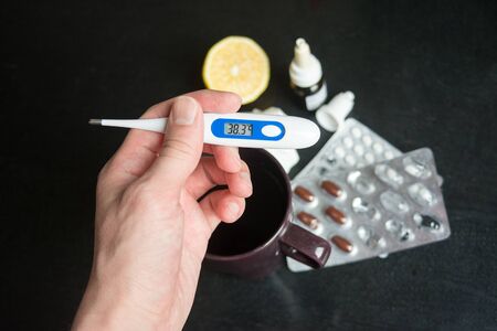 electronic thermometer in hand shows high temperature, fever, disease