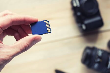 flash card in hand on camera background, memory card for DSLR camera, flash drive, photo storage,...