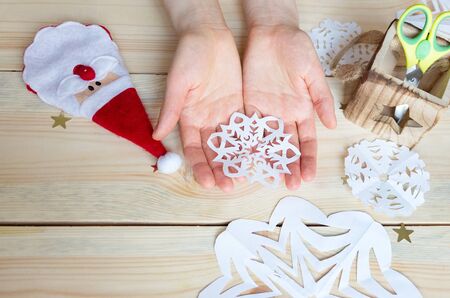 the girl makes a homemade snowflakes cut out of paper, preparation for the new year, Christmas, home decorationの写真素材