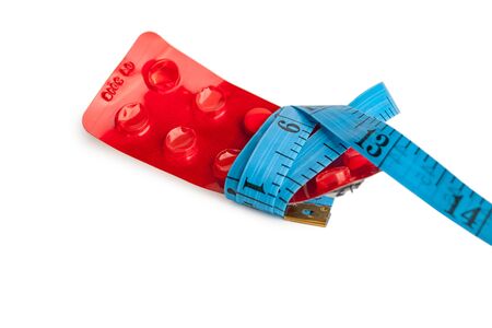 blister with tablets and tied with measuring tape, the concept of taking drugs for weight loss and maintain the figure, the harm of supplements for weight loss, isolated on white backgroundの写真素材