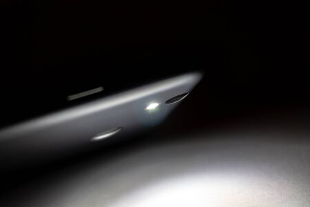 flashlight shining in the dark, flashlight in the smartphone on a dark backgroundの写真素材