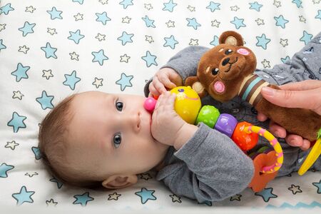 little happy motivated child is playing with dangling rattles, toys for newborn, first toyの写真素材