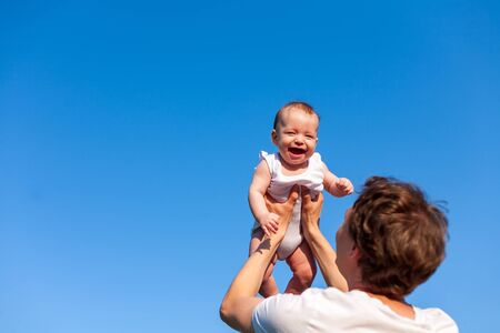 little baby in father's arms against blue sky , father's day, fatherhood, happy baby