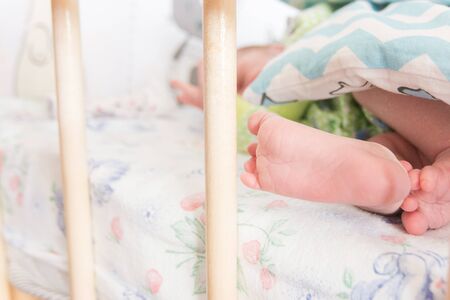  newborn baby legs in baby cot, the concept of motherhood, child careの写真素材
