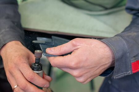 tool for sanding and polishing edges in the hands of a tailor seamstress tanner, polisher for leather fabric, manual labor close-upの写真素材