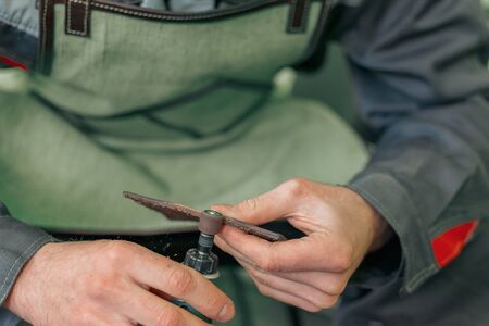 tool for sanding and polishing edges in the hands of a tailor seamstress tanner, polisher for leather fabric, manual labor close-upの写真素材