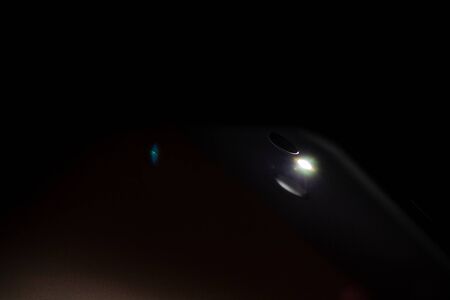 flashlight shining in the dark, flashlight in the smartphone on a dark backgroundの写真素材