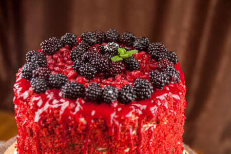 Cake baked from a sponge cake, decorated with ripe juicy blackberries, black raspberries, close-upの写真素材