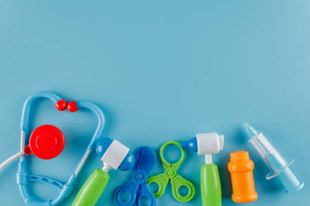toy set of tools for treatment, for playing doctor, toy stethoscope, hammer, syringe, pliers and pills, blue background, flat layの写真素材