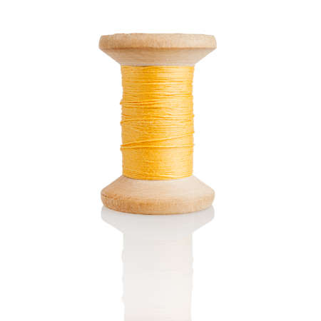 Wooden spool with yellow threads, embroidery and sewing, tailor isolated on a white background, close-upの写真素材