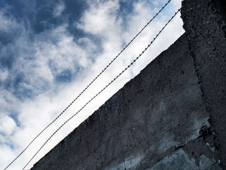 High concrete fence with stretched barbed wire, closing of visits, closed borders, isolation
