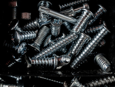 Bolts screws self-tapping screws of various shapes and sizes for connecting fastener elements isolated on a dark background close-upの写真素材