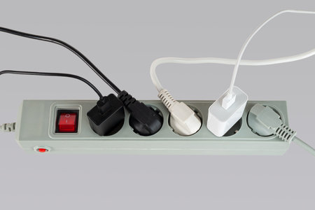 Various electrical plugs from electrical appliances connected to an extension cord isolated on a white background close-upの写真素材