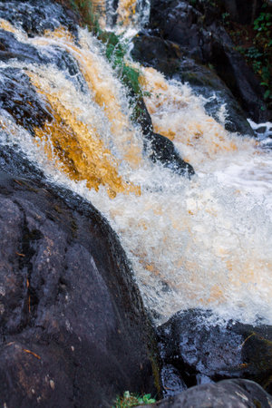 a bubbling fast cold river with cliffs and waterfalls, a mountain river with rapids and rocksの写真素材