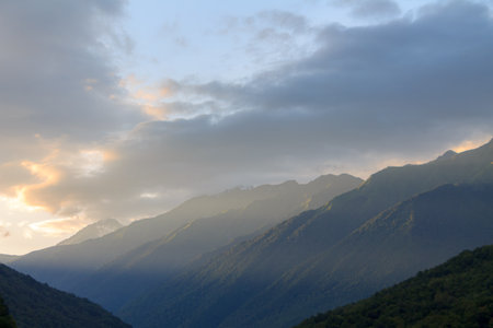 Fog and clouds in the mountains against the backdrop of the setting sun, changeable weather in the...