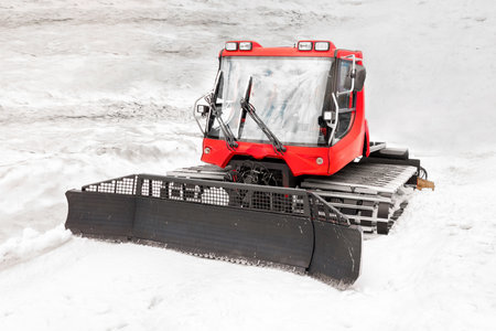 heavy snowplow with a bucket on tracks, grader for rolling snow on mountain slopes, ski slopes,...