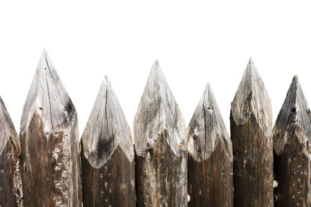 Ancient fortification fence made of wooden stakes, vintage building, defensive historical structure close-up isolated on a white backgroundの写真素材