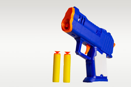 Children's toy gun loaded with foam bullets with suction cups, children's game shootout hitting the target, isolated on a gray background close-upの写真素材
