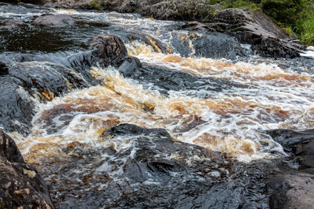 a bubbling fast cold river with cliffs and waterfalls, a mountain river with rapids and rocksの写真素材