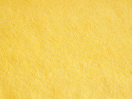 Stitched seam on yellow fabric textile background close-up selective focusの写真素材