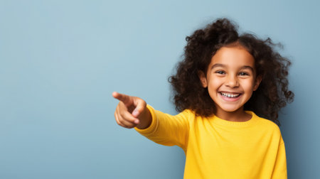 cheerful smiling child points with finger, bright background, copyの素材